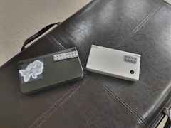 A New 3ds xl, and a dsi. The New 3ds xl is on the left, is black, and has a reshiram sticker on it. The dsi is on the right, is white, and has no visible sticker on it.